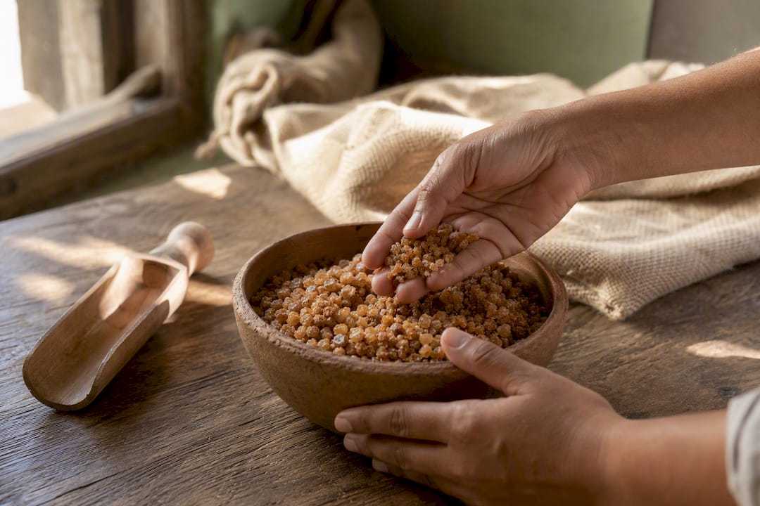 Hands inspecting organic panela sugar granules