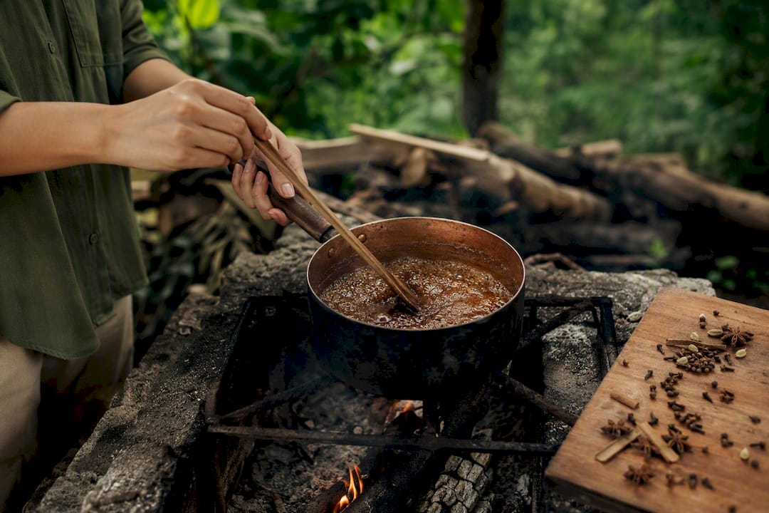 Hands stirring panela chai syrup on stove