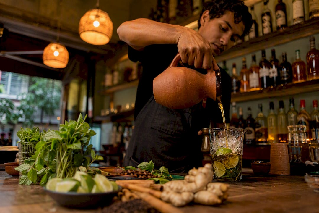 Bartender pouring panela syrup into cocktail glass