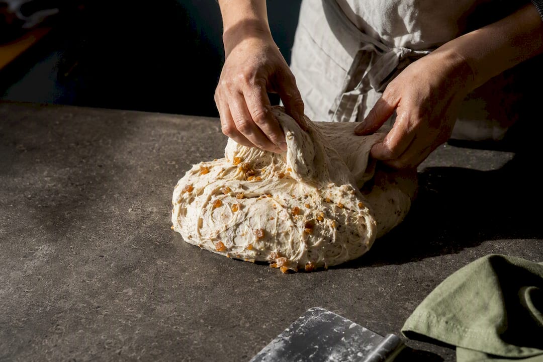 Baker folding panela into sourdough dough