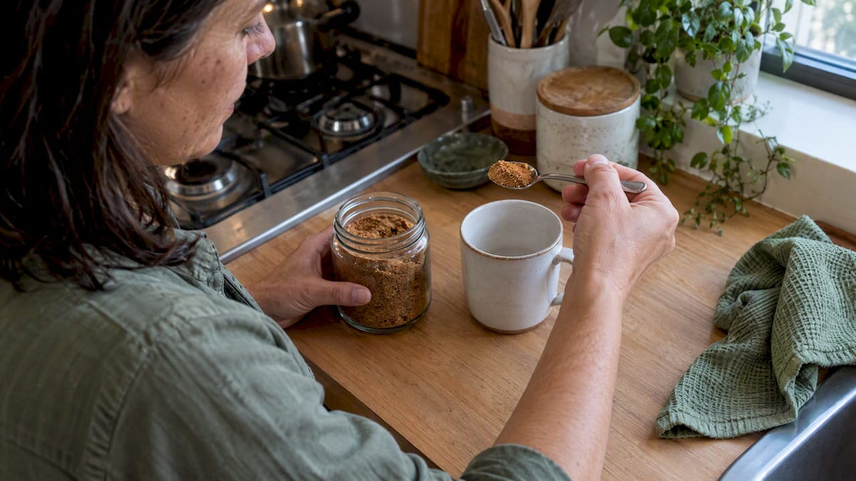 A teaspoon of panela measured beside a mug